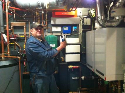 Middle aged man wearing a jean jacket admiring his Viessmann boiler system after performing a boiler clean in the City of Calgary.